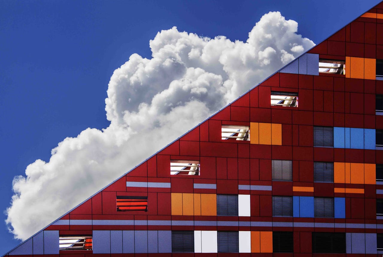 why-choose-us Colorful modern building facade against a backdrop of dramatic clouds and bright blue sky.
